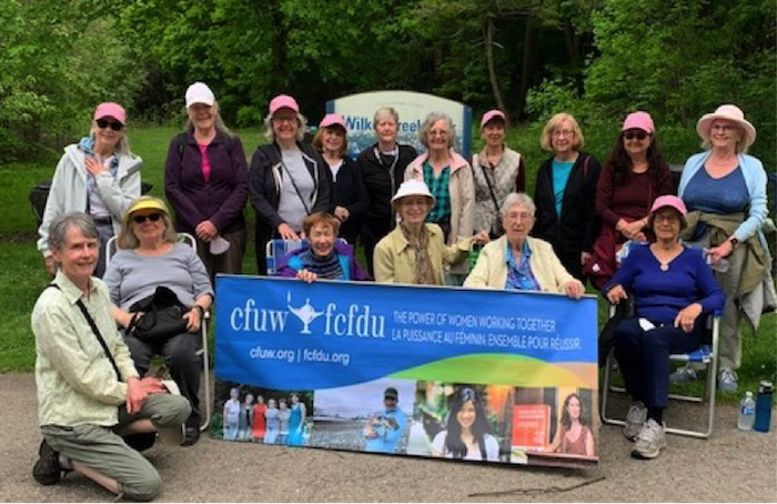 men and women standing with club banner
